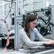 Business technology: woman working on a computer in a room with electrical wires and other tech equipment